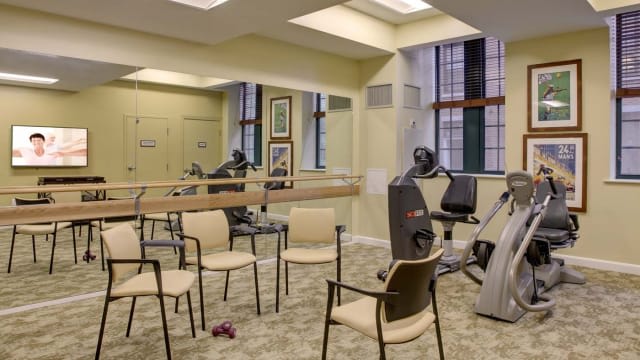 A small exercise room equipped with fitness machines, chairs, and mirrors.