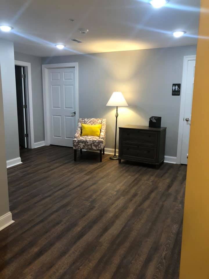 A modern and cozy room with a chair, lamp, and wood flooring.