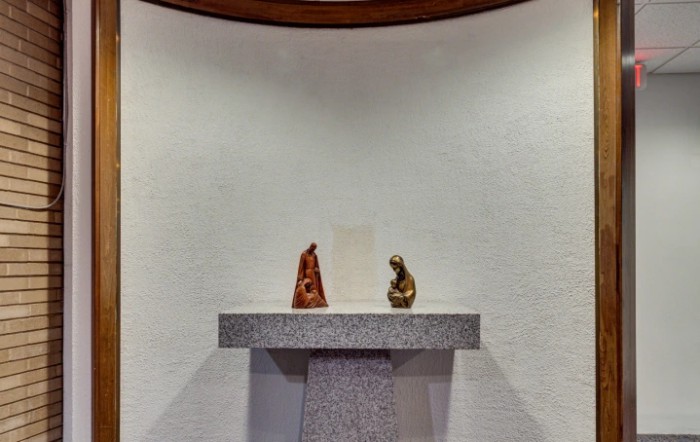 A minimalist altar with two statues in a modern religious setting.