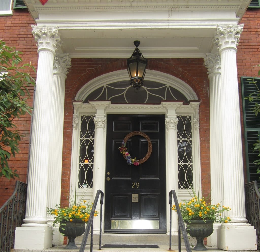 Elegant front entrance with columns and a decorative wreath on the door.