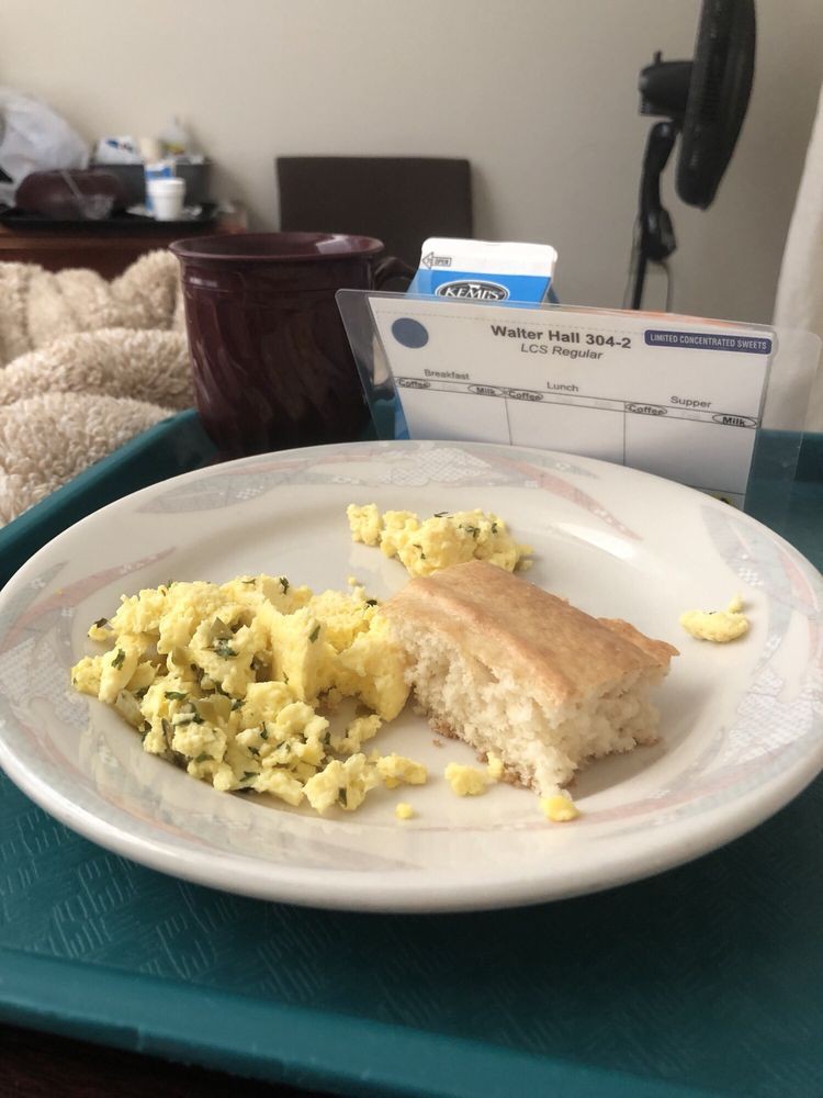A hospital meal consisting of scrambled eggs and a biscuit on a tray.