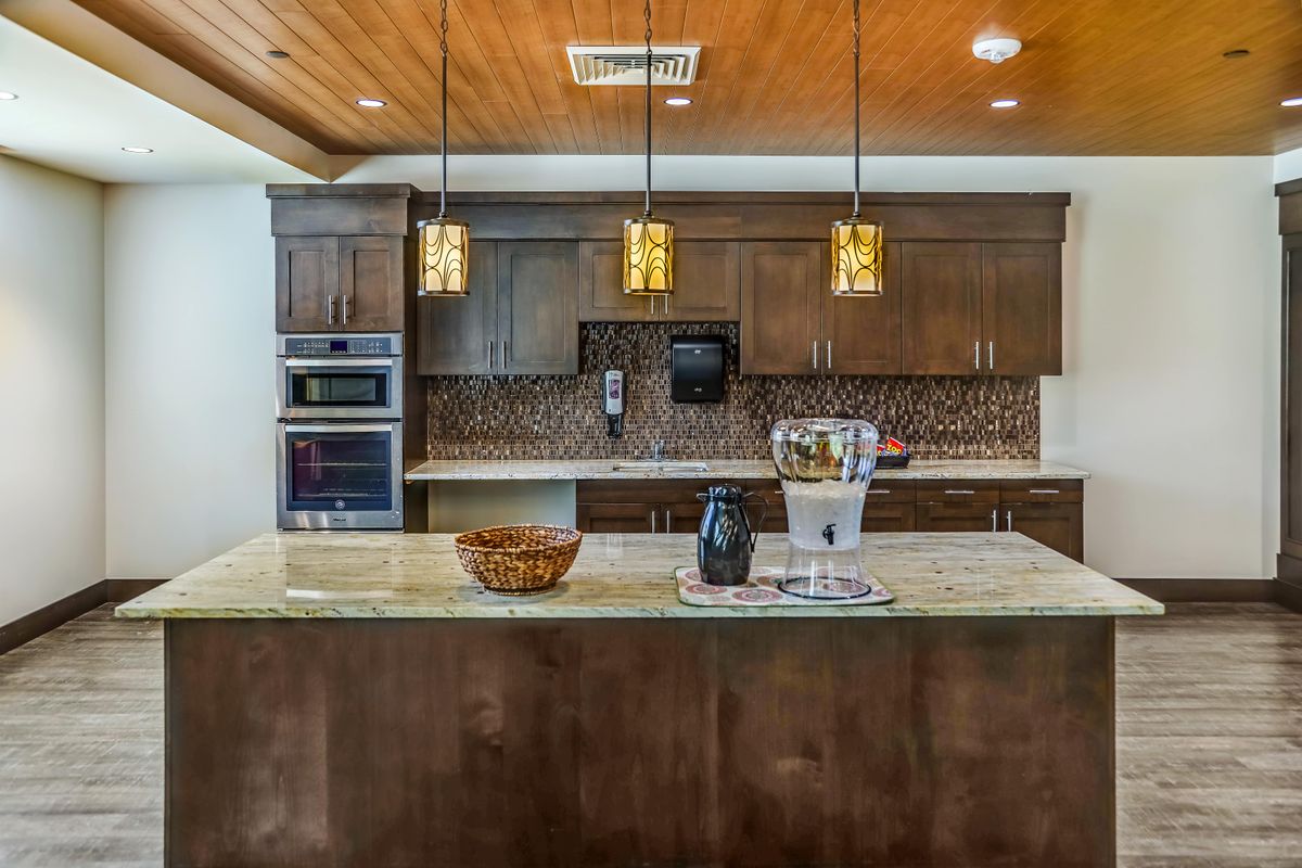 A modern kitchen with a large island, pendant lighting, and sleek wooden cabinets.
