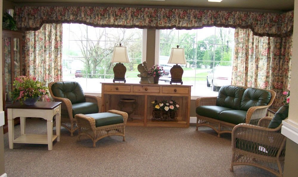 A cozy waiting room with comfortable chairs, decorative lamps, and large windows.
