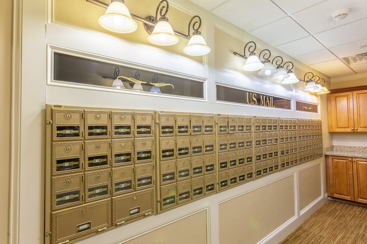 A hallway lined with multiple mailboxes under bright indoor lighting.