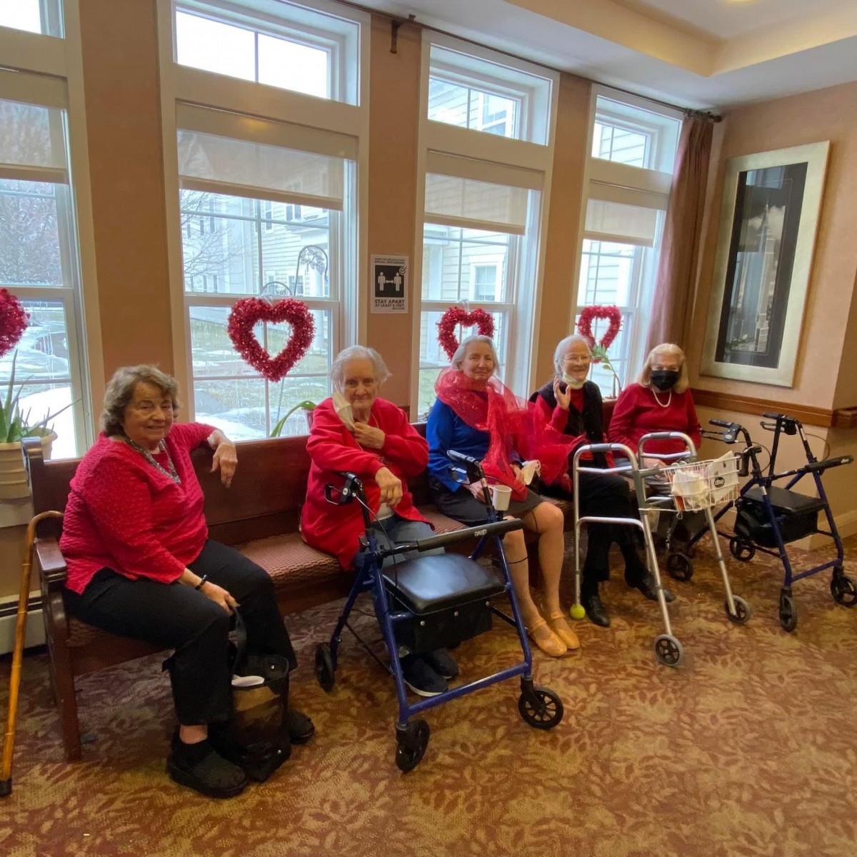 A group of seniors sitting together in a decorated room with Valentine's Day hearts on the windows.