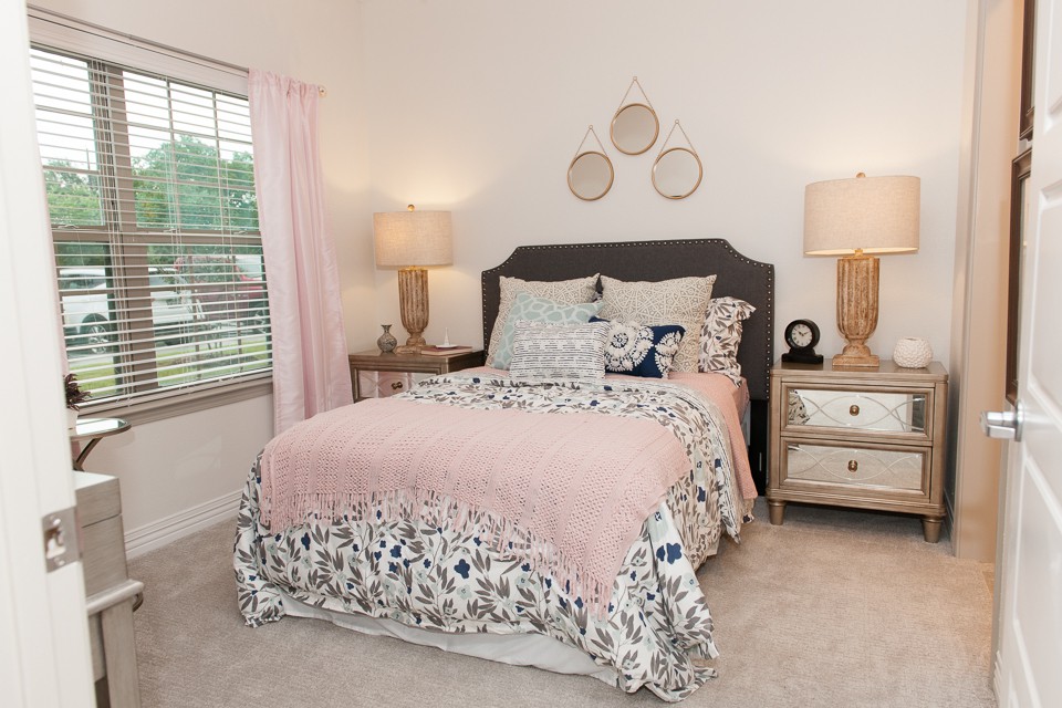 A cozy bedroom with a neatly made bed, decorative pillows, and warm lighting from bedside lamps.