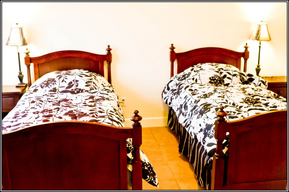 A neatly arranged bedroom with two twin beds featuring floral bedding.