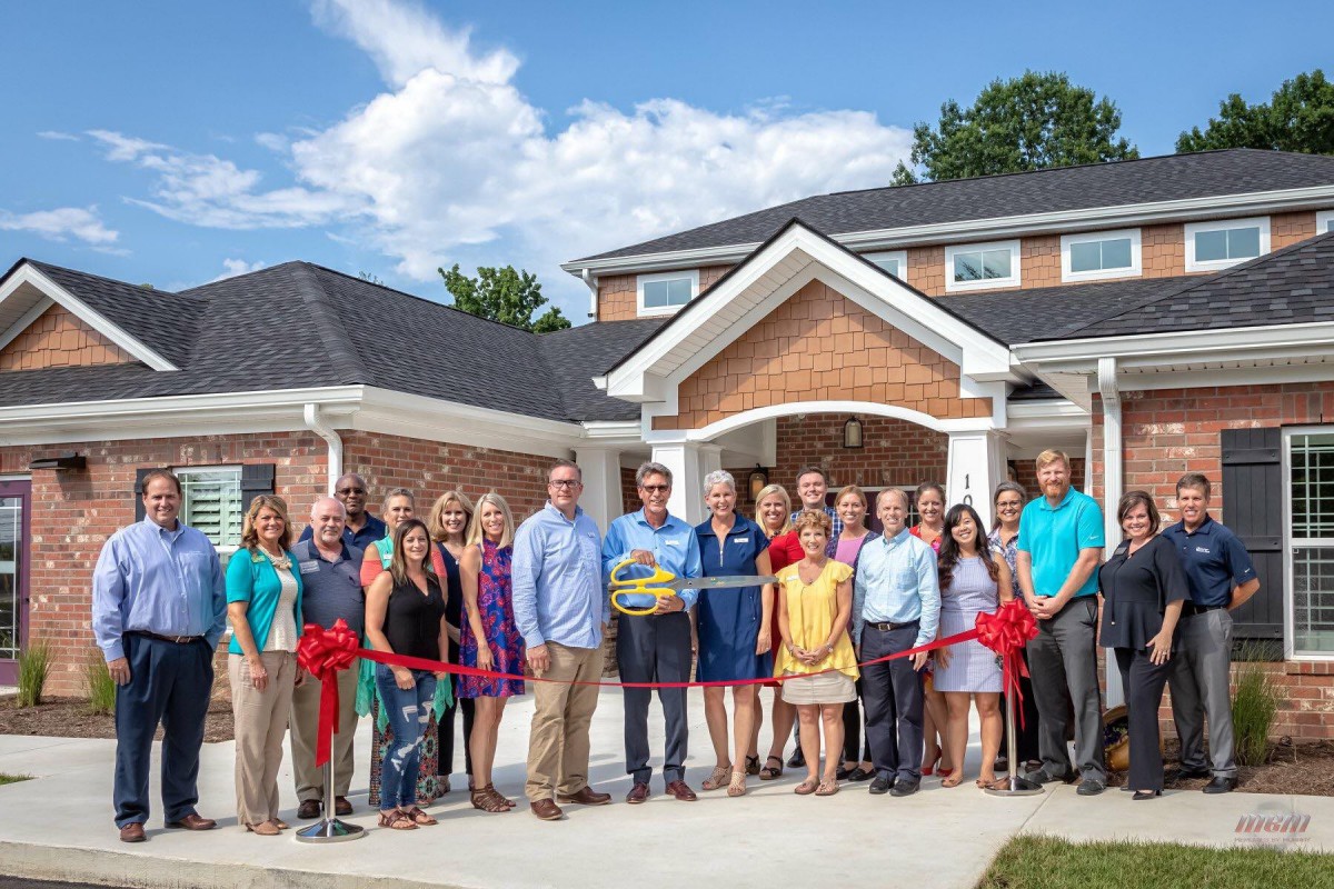 A group of people gathered for a ribbon-cutting ceremony in front of a building.