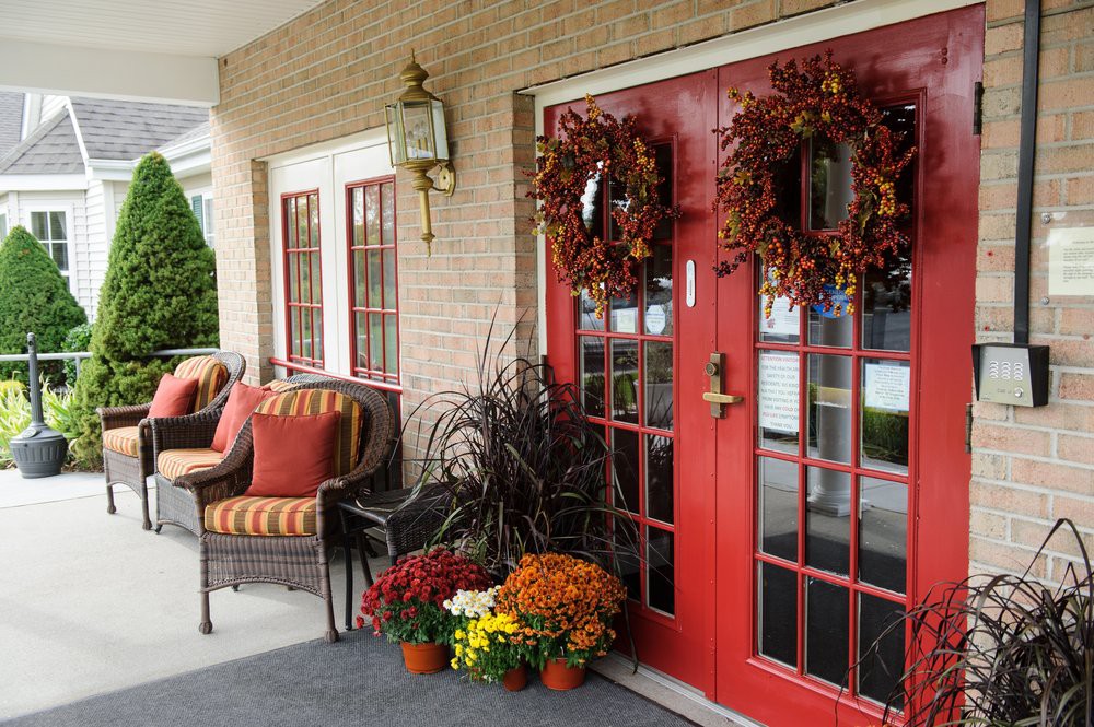 A welcoming front porch adorned with autumn wreaths, potted plants, and comfortable seating.