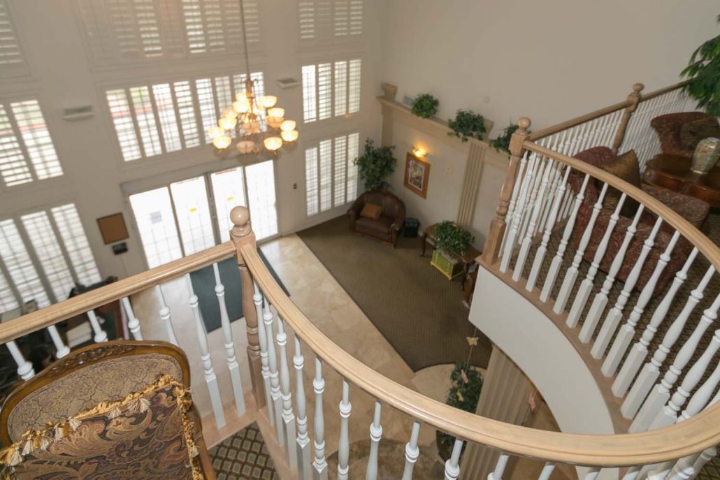 A spacious foyer with a grand staircase, chandelier, and large windows.