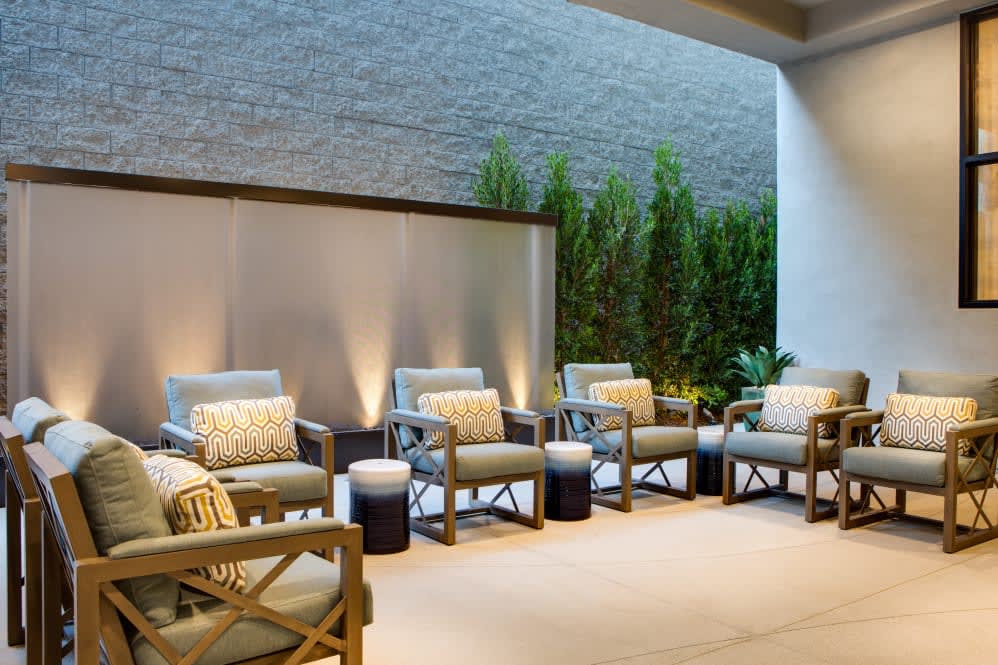 A stylish outdoor seating area with comfortable chairs, cushions, and ambient lighting.