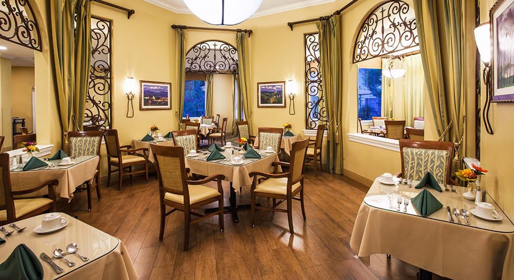 An elegant dining room with neatly arranged tables and chairs, featuring sophisticated decor and warm lighting.