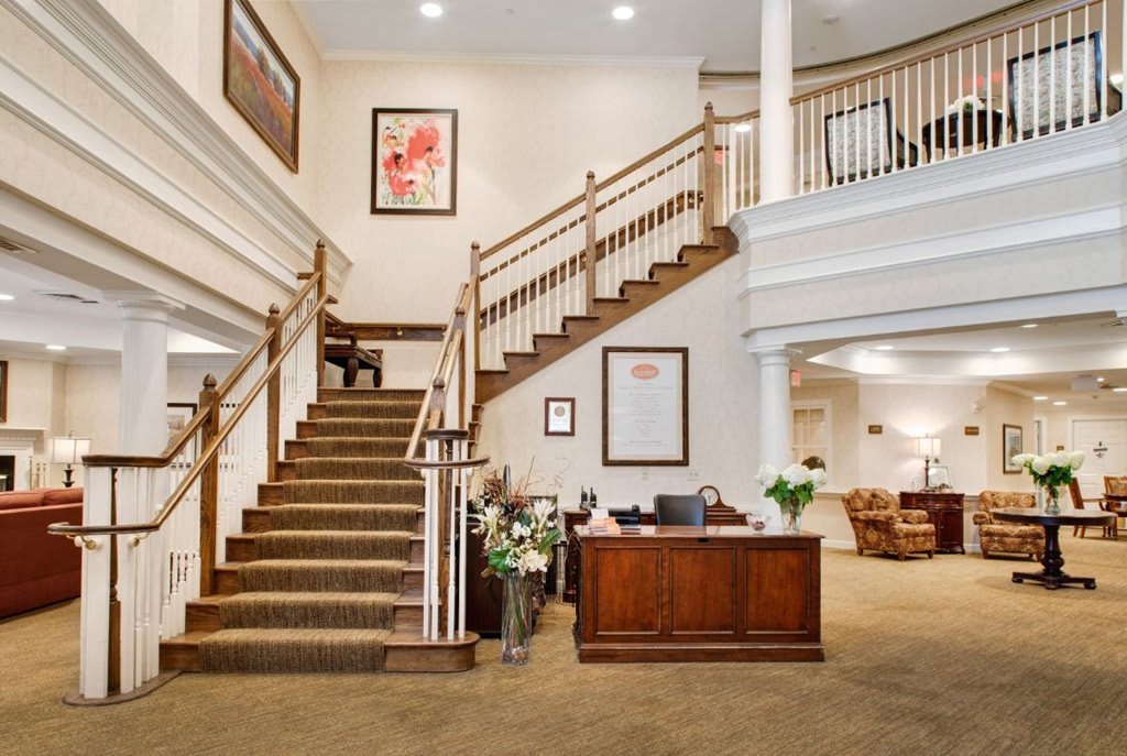 A spacious and elegant lobby with a grand staircase and reception desk.