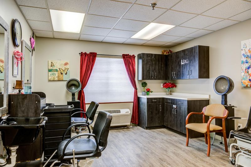 A well-organized salon interior featuring chairs, cabinets, and a sink with vibrant red curtains.