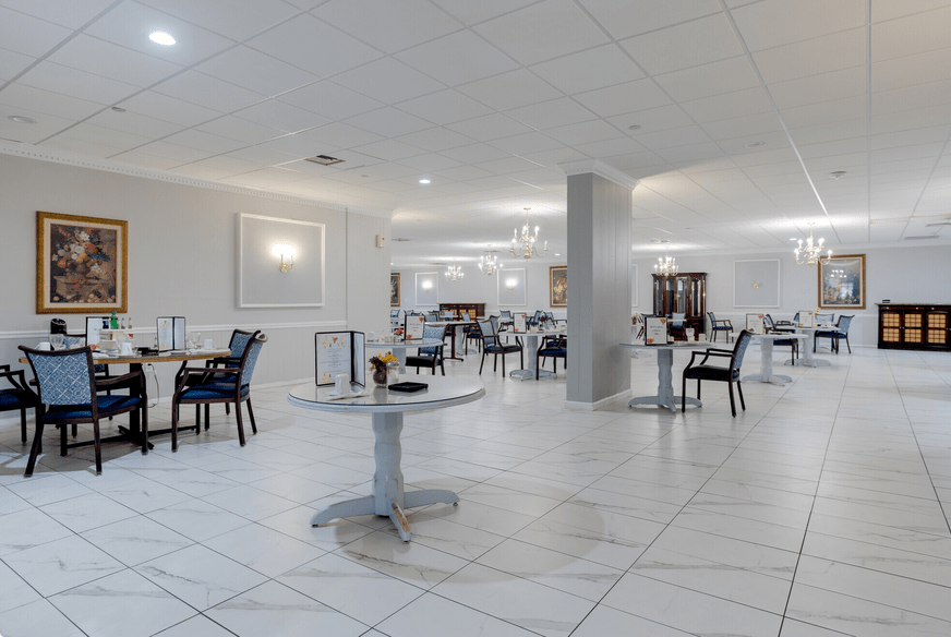 A modern restaurant dining area with white decor and neatly arranged tables and chairs.