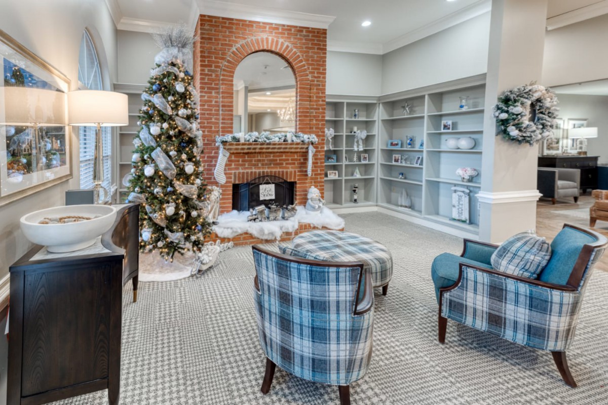 A cozy living room decorated for the holidays with a Christmas tree and a brick fireplace.