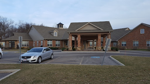 A modern residential building with a welcoming entrance and a parked silver car in the foreground.