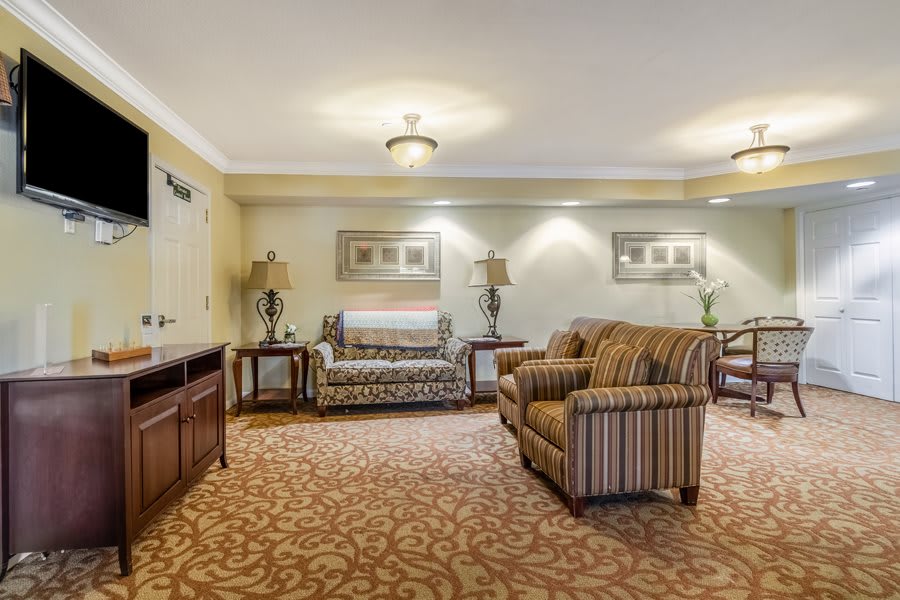 A cozy living room with sofas, decorative lamps, and patterned carpeting.