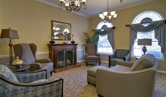 A cozy living room with elegant furniture and a fireplace, featuring chandeliers and ample seating.