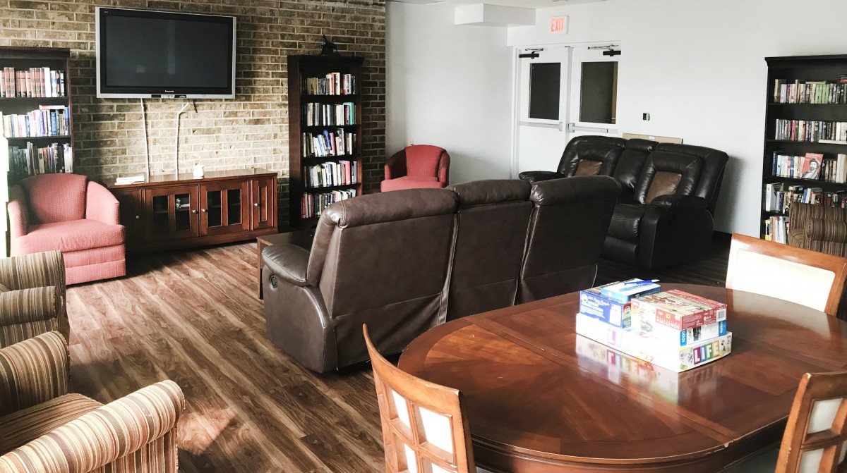 A cozy living room with a large couch, a bookshelf, and a television.