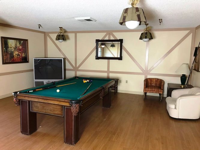 A cozy game room featuring a pool table, television, and comfortable seating.