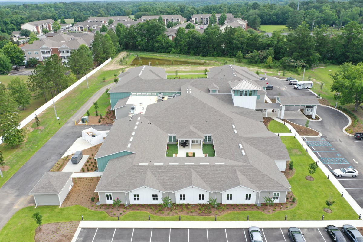 An aerial view of a large building surrounded by green spaces and parking areas.