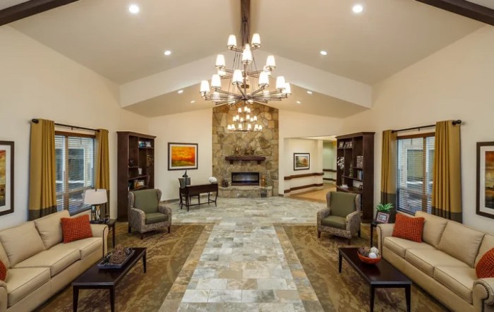 A spacious and elegantly designed living room featuring a central chandelier, a stone fireplace, and comfortable seating.