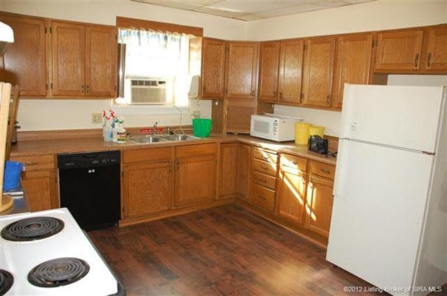 A cozy kitchen featuring wooden cabinets, a microwave, and a refrigerator.