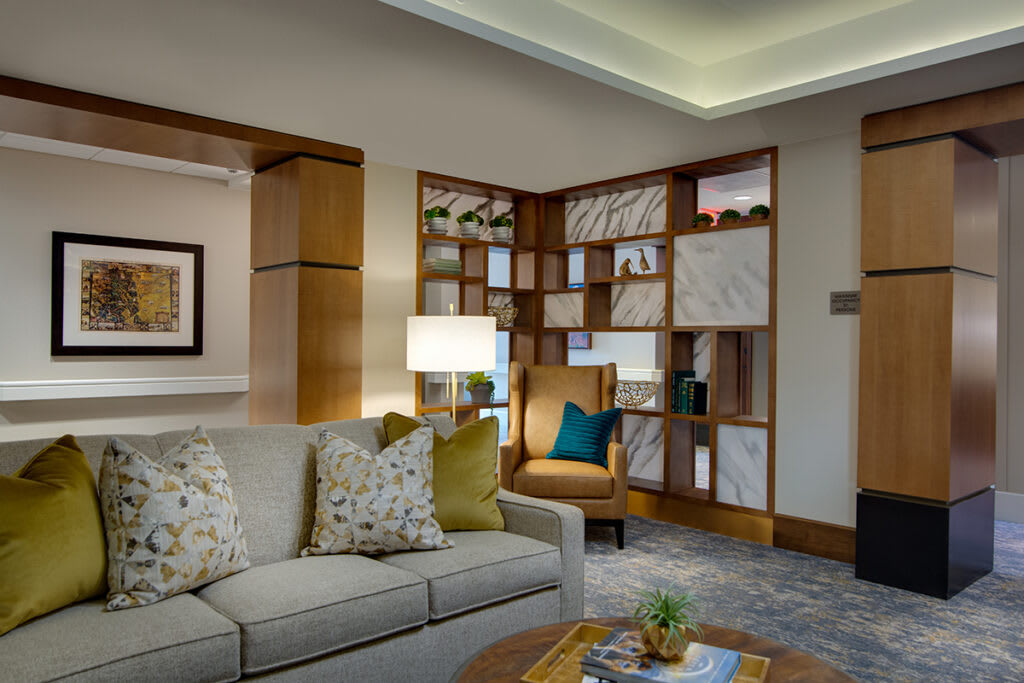 A cozy living room with a sofa, armchair, and decorative shelves.