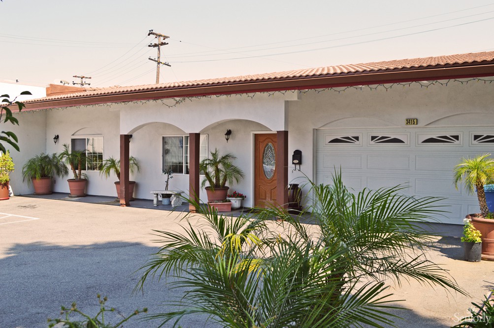 A single-story house with a garage and palm plants in the driveway.