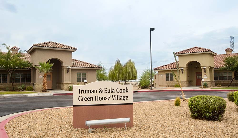 Entrance sign to the Truman & Eula Cook Green House Village with buildings and landscaping in the background.
