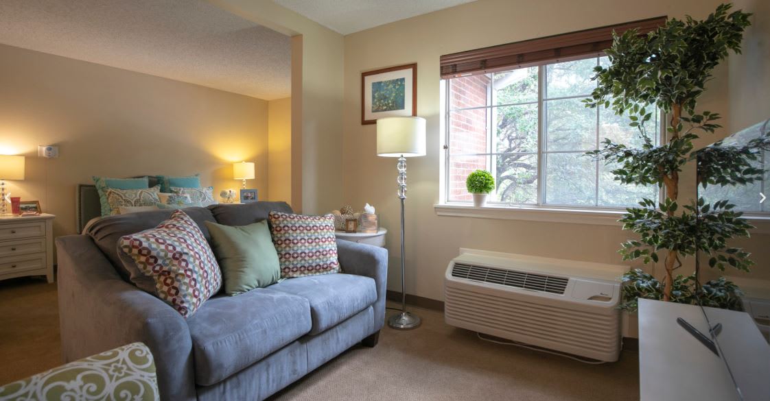 A cozy living room with a sofa, lamp, and large window.