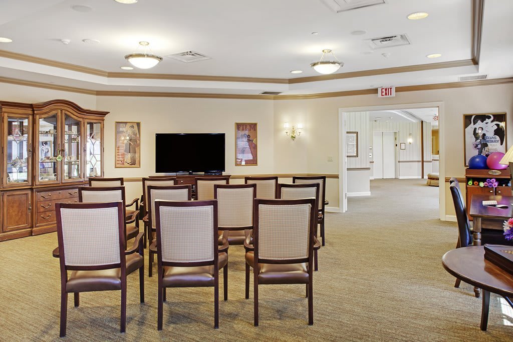 An interior view of a conference room with rows of chairs facing a television on the wall.