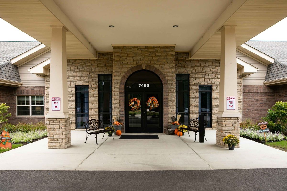 A building entrance with a stone facade and arched doorway, featuring outdoor benches and seasonal decorations.