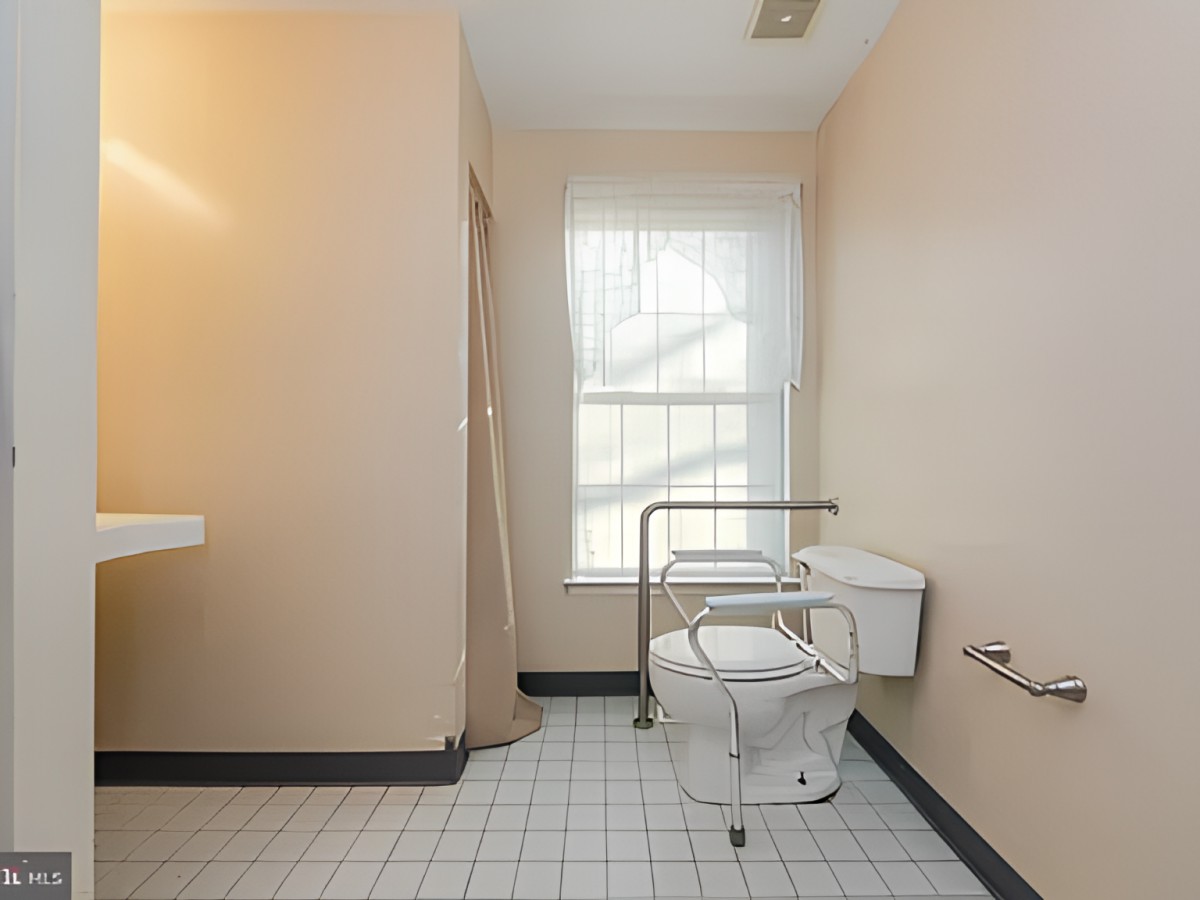 An accessible bathroom with grab bars and a tiled floor.