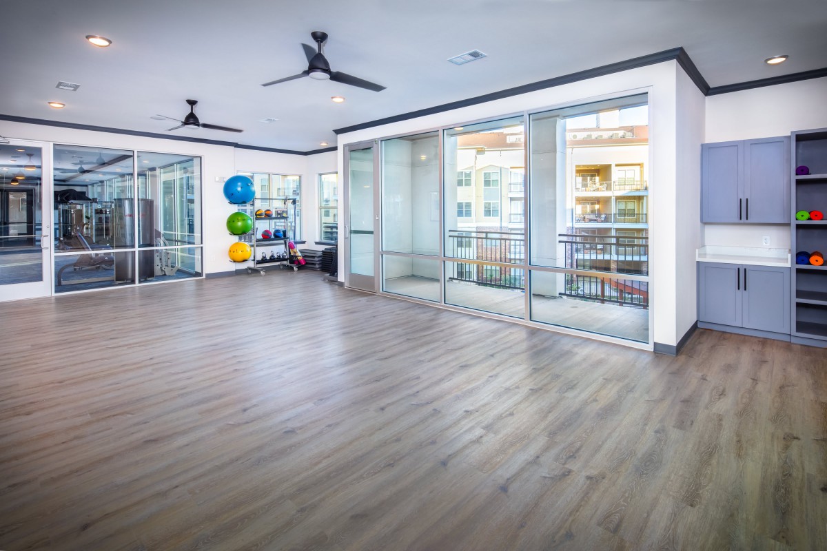 Spacious and bright yoga studio with wood flooring and fitness equipment.