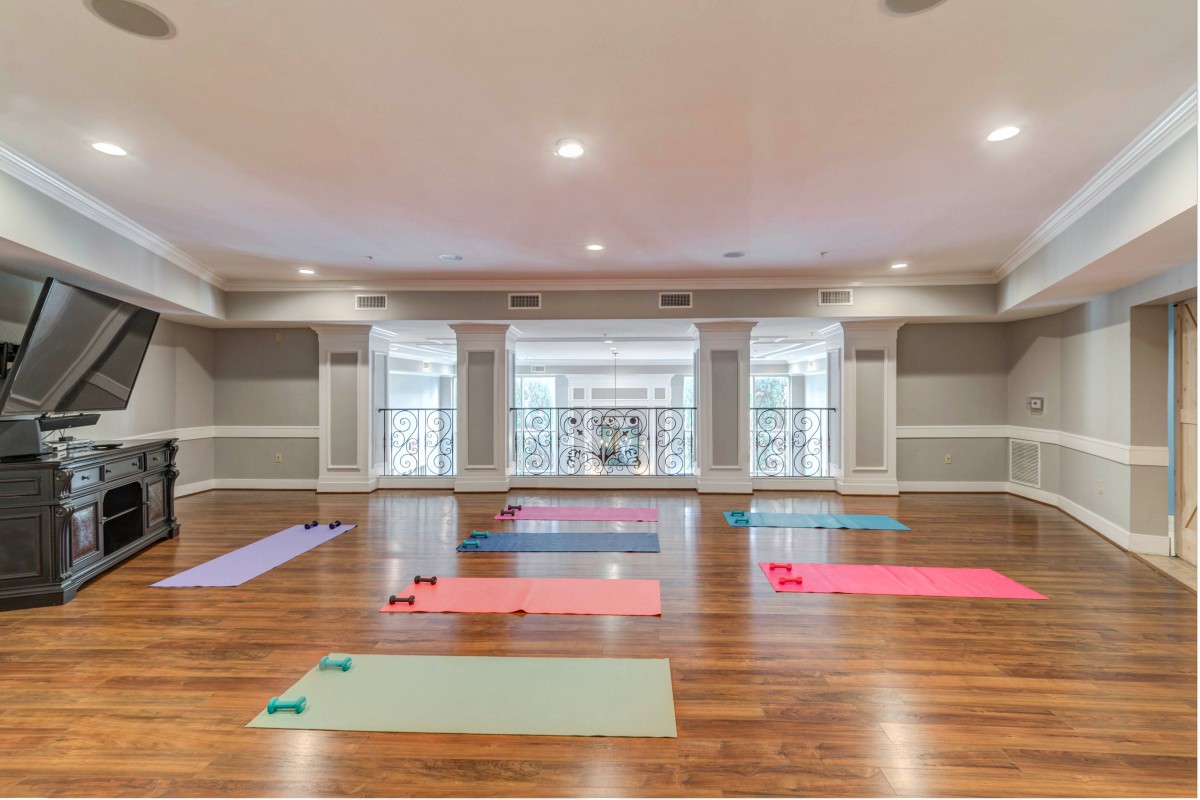 An empty yoga studio with brightly colored exercise mats laid out on a polished wooden floor.