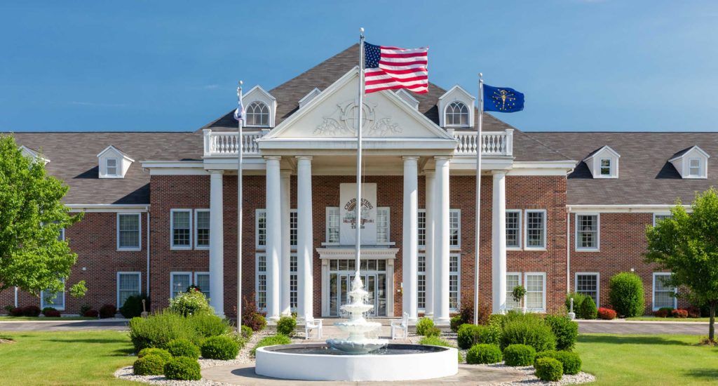 A majestic building with columns and a fountain, adorned with American and state flags.