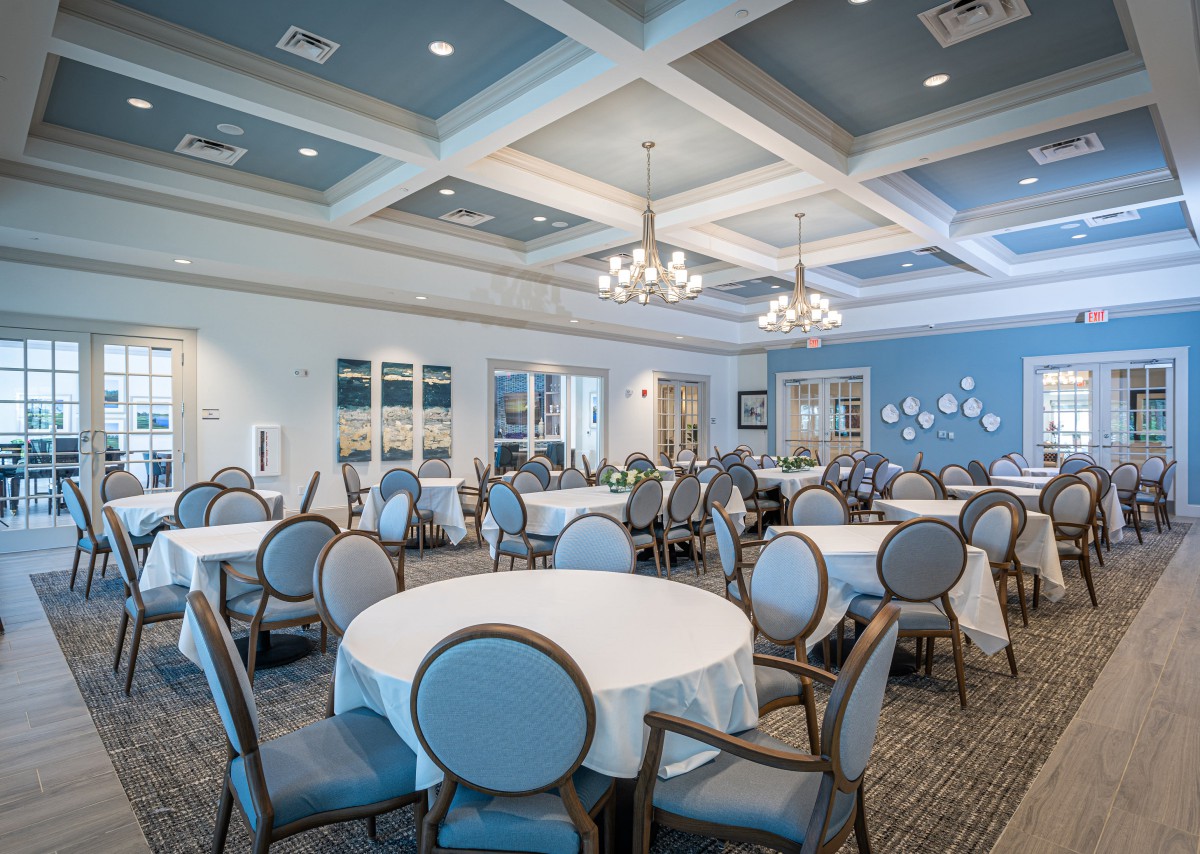 An elegant banquet hall with round tables and chandeliers, ready for an event.