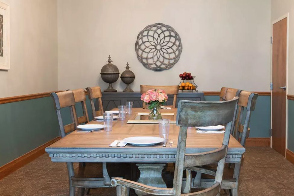 A beautifully set dining room table with rustic chairs and elegant wall decor.