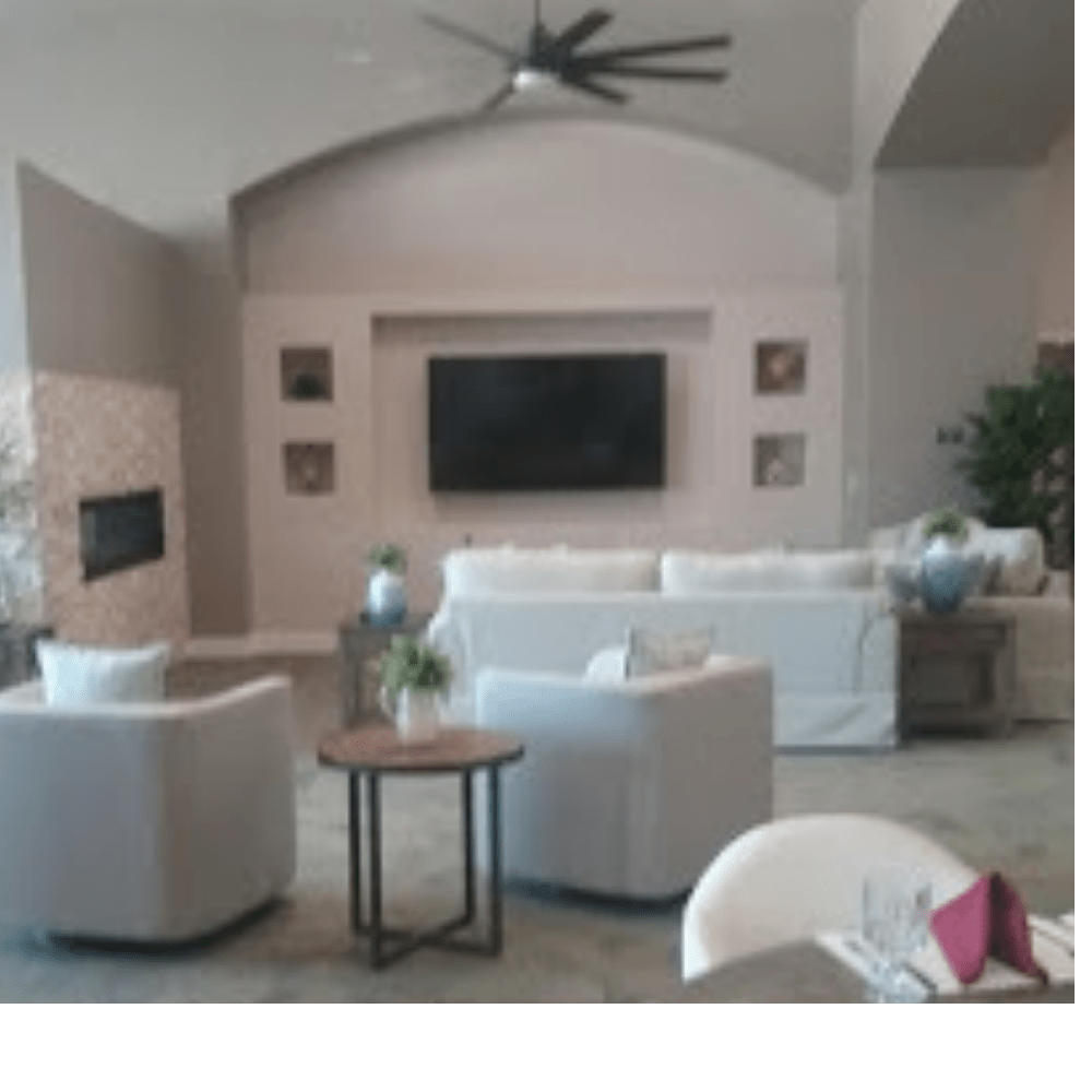 A modern living room with white sofas, armchairs, a large television, and stylish decor.