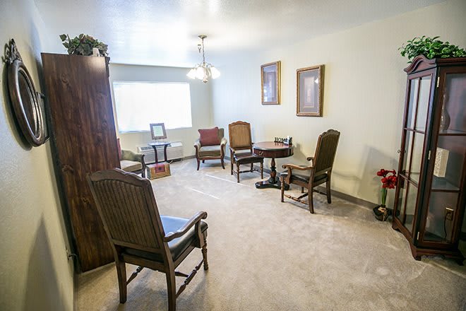 A cozy living room with several chairs, a small table, and abundant natural light.