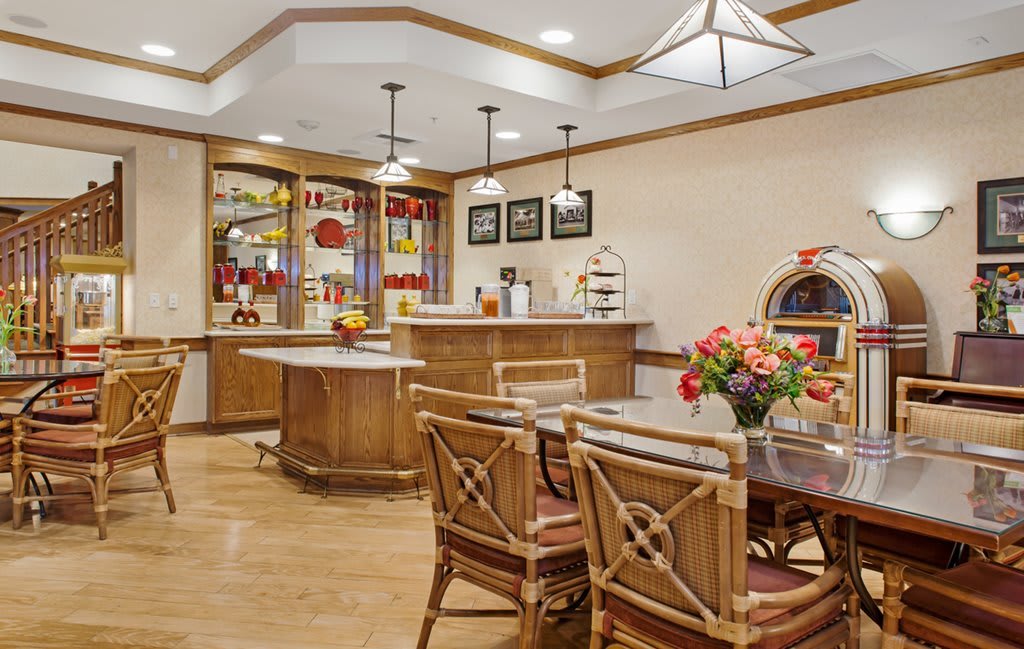 A cozy kitchen and dining area featuring wooden furniture, modern lighting, and a vibrant flower arrangement.