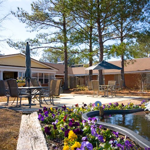 A serene outdoor space featuring a beautifully landscaped garden with vibrant flowers, comfortable seating, and sunlight filtering through the trees.