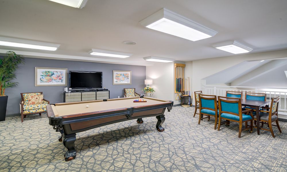 A well-furnished game room featuring a pool table and seating area with a television.