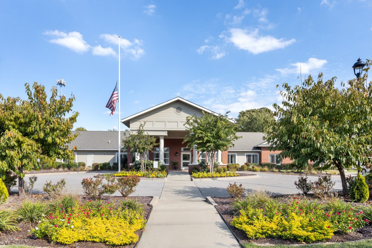 A well-maintained building with a flagpole and landscaped garden under a clear sky.