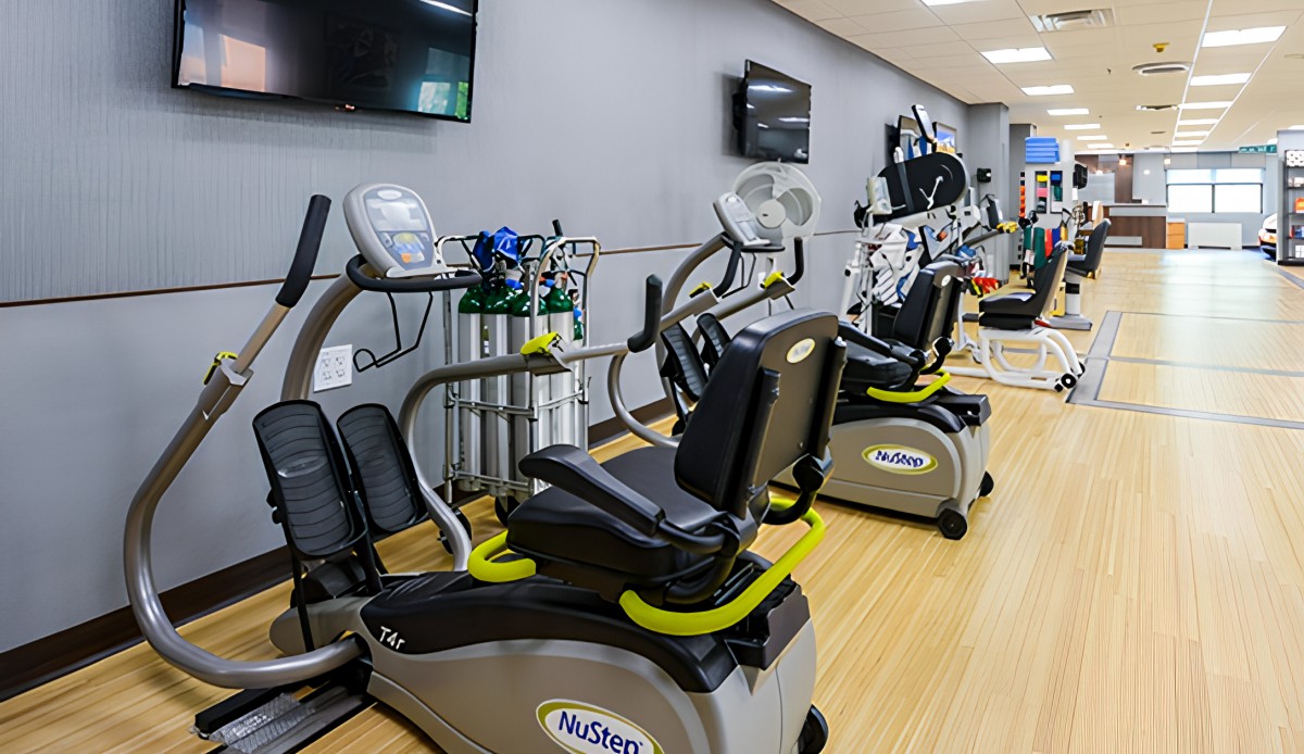 A well-equipped gym with exercise machines and televisions.