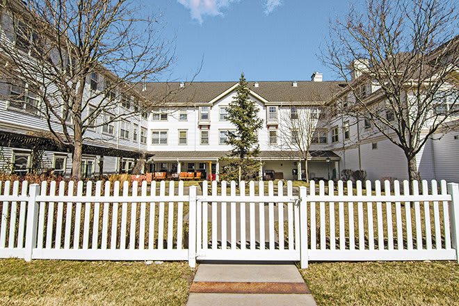 A residential building with a white picket fence and clear blue sky.