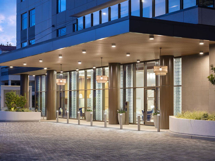 A modern building entrance illuminated at night with glass doors and bright lights.