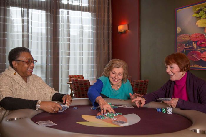 A group of elderly friends enjoying a lively card game together indoors.